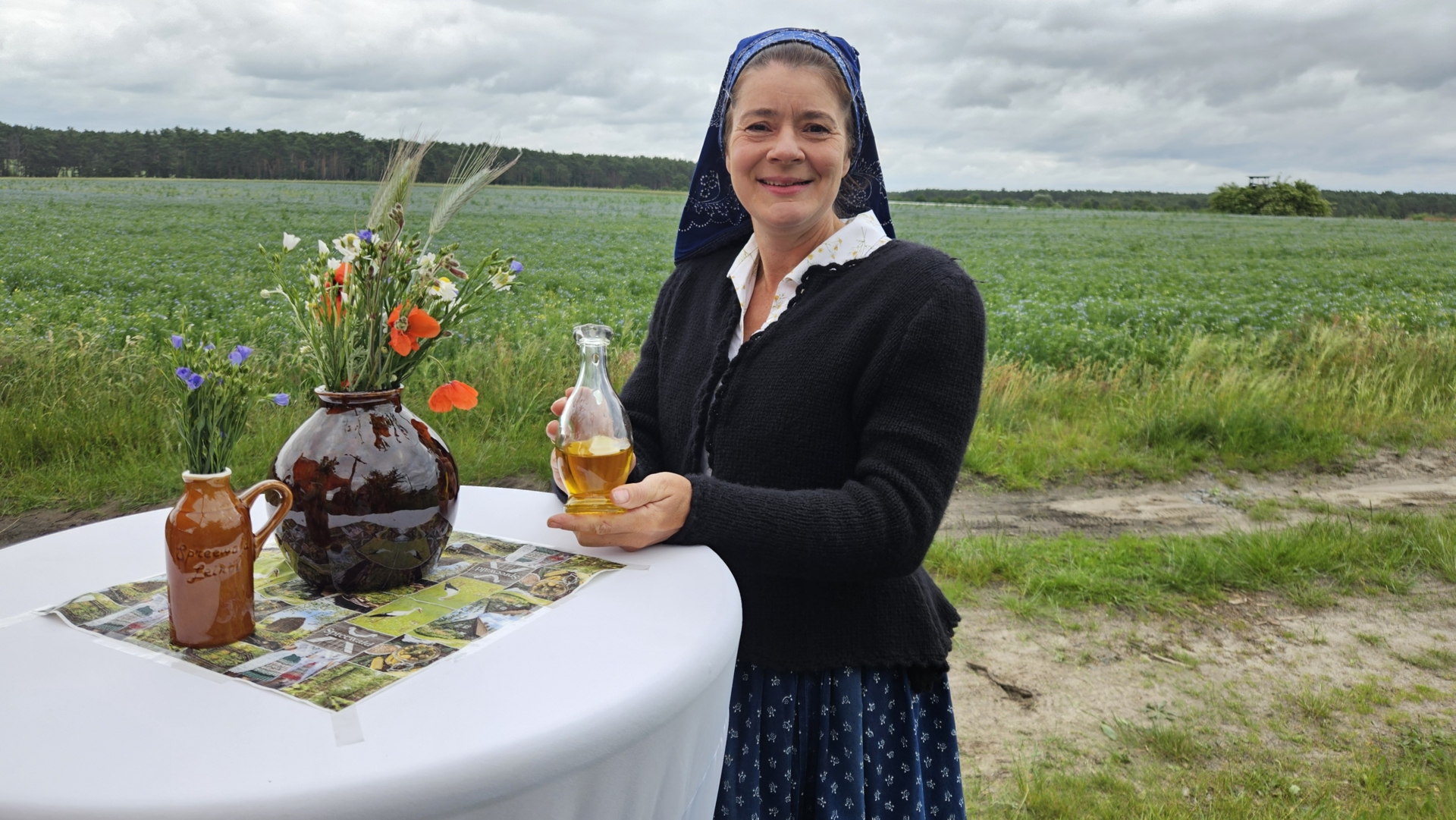 Die Schlepziger Kahnfährfrau Yvonne Huber in sorbischer/wendischer Arbeitstracht präsentiert frisch gepresstes Leinöl. Foto: Dörthe Ziemer
