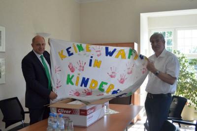 Bürgermeister Heiko Müller übergibt die Plakate mit Botschaften an Landrat Roger Lewandowski.