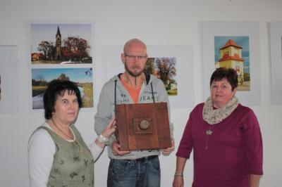 Dagmar Leitel, Dirk Felgendreher und Dagmar Buchmann bestaunen eine alte Plattenkamera aus Holz.