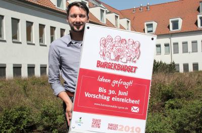 Jens Mörsel, verantwortlich für das Bürgerbudget, präsentiert das Werbeplakat für das Bürgerbudget 2019