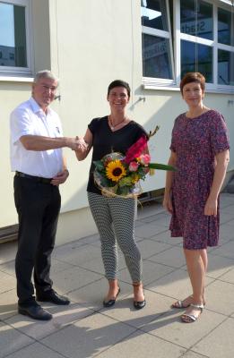 Bürgermeister Heiko Müller und Wirtschaftsförderin Babett Ullrich begrüßen Leona Heymann (Mitte) herzlich mit einem bunten Blumenstrauß zur ersten Beratung im Falkenseer Bürgeramt.