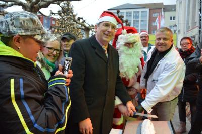 Foto: Bürgermeister Dr. Oliver Hermann schneidet mit dem Weihnachtsmann und Bäckermeister Lars Erfert den Stollen an I Foto: Martin Ferch