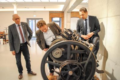Lars Schladitz (r.) führt Sebastian Steineke (M.) und Dr. Ronald Thiel (l.) eine voll funktionstüchtige, gut 100 Jahre alte Druckmaschine vor. Foto: Beate Vogel