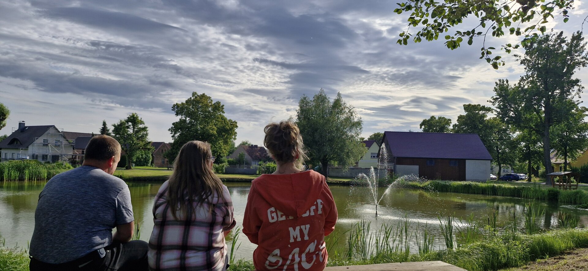 Ortsbeirat  schaut auf die Fontäne im Dorfteich in Ossendorf