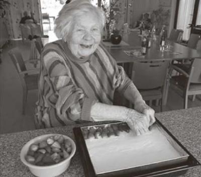 Die 92-jährige Melitta Zorn belegt den Kuchen, den die Senioren in der Tagespflege gemeinsam gebacken haben, mit Erdbeeren. Bildquelle: Stefan Krüger, BRK Würzburg