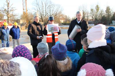 Das Bild zeigt Bürgermeister Heiko Müller und Baudezernent Thomas Zylla beim Befüllen der Zeitkapsel mit den Kindern des Hortes der Lessing-Grundschule.