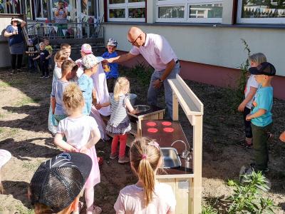 Bürgermeister Dr. Ronald Thiel enthüllt die Matschküche im Garten der Kita „Kinderland“. Foto: Beate Vogel