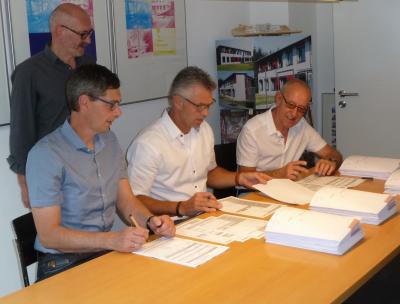 Die Ortsbürgermeister Winfried Erbes, Michael Brennemann und Kurt Müller bei der Unterzeichnung im Büro von Hubertus Jäckel (stehend); Foto: Arnold Grings
