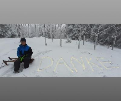 Auf dem Bild sieht man Lars auf dem Schlitten neben einem groß in den Schnee geschriebenem "DANKE".