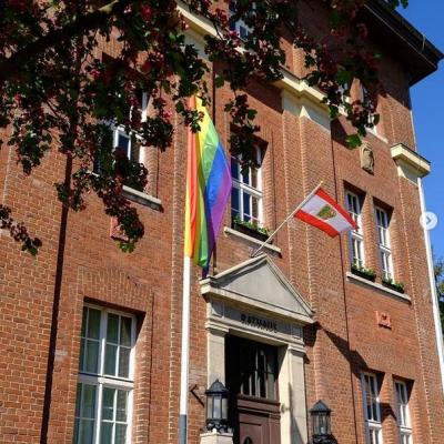 Bürgermeisterin und Gleichstellungsbeauftragte hissen Regenbogenflagge am Rathaus