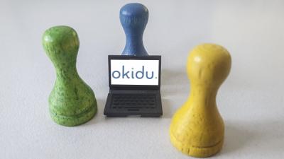 Drei Spielfiguren um einen Laptop mit Okidu Logo herum (Bild vergrößern)