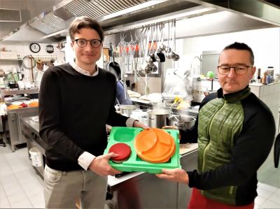 Der Vorsitzende des Haunetaler Vereinsrings Timo Lübeck zeigt mit Essen-auf-Rädern-Fahrer Lars Stein in der Bürgerhausküche die neuen Geschirrboxen.