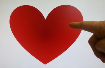 Das Foto zeigt einen Finger, der auf ein rotes Herz zeigt.
