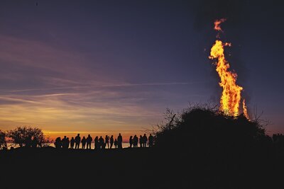 pixabay | Zu sehen im Vordergrund ein brendendes Feuer, im Hintergrund darumstehend Menschen