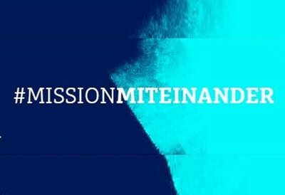 Das Foto zeigt den in weiß geschriebenen Schriftzug #MISSIONMITEINANDER auf rechts dunkelblauem und links hellblauen Hintergrund