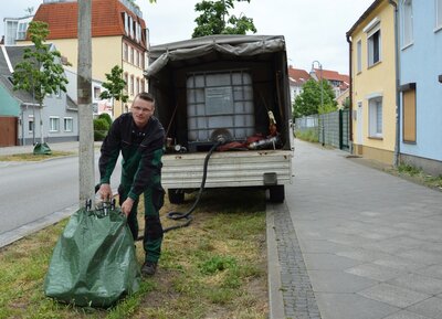Alexander Reichwald vom Stadtbetriebshof füllt Bewässerungssäcke in der Rathausstraße auf I Foto: Martin Ferch