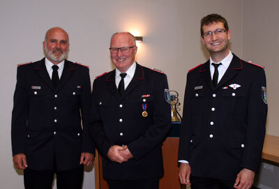 Hohe Auszeichnung für Bürgermeiste ra.D. Claus Hell (Mitte), Kay Sierk (KFV Pinneberg, links) zeichnete ihn mit der Deutschen Feuerwehr Ehrenmedaille aus, Wehführer Lasse Krüger gratuliert.