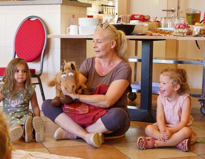 Unser Bild zeigt Ruby, Erzieherin Silke Damsch und Lina bei einem Kreisspiel. Die Handpuppe Rossi zog Instrumente aus der Tasche, die die Kinder benennen sollten.