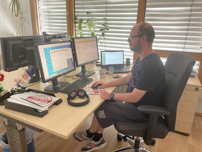 Christian Klimm an seinem Arbeitsplatz. Er sitzt vor einem Computer.