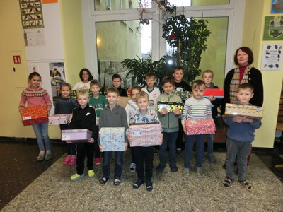 Unser Foto zeigt Kinder mit liebevoll gestalteten Päckchen und die Rektorin der Schule Annelies Rogler-Unglaub.