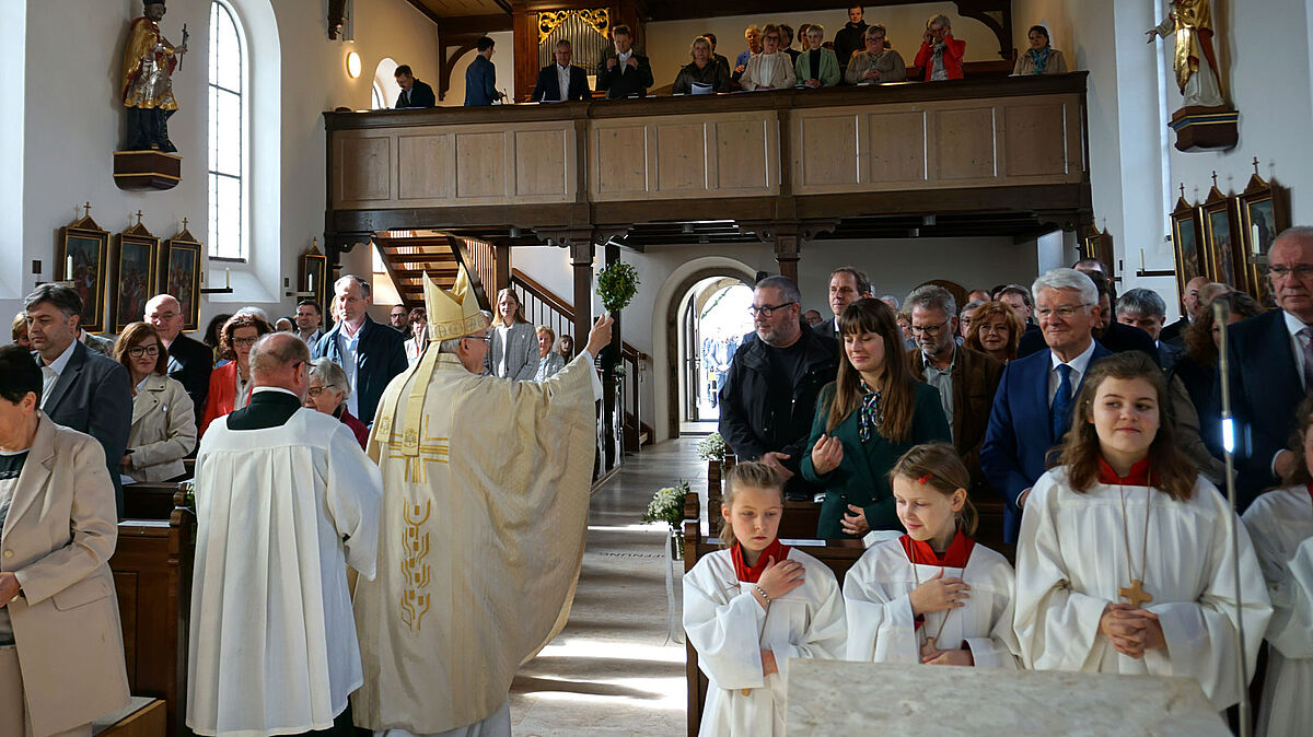 Bischof Rudolf zog durch das Kirchenschiff und besprengte das sanierte Gotteshaus und Gläubige mit Weihwasser. Auch Landrat Franz Löffler und sein Vorgänger Theo Zellner waren zur Feier gekommen (rechte Kirchenbank).