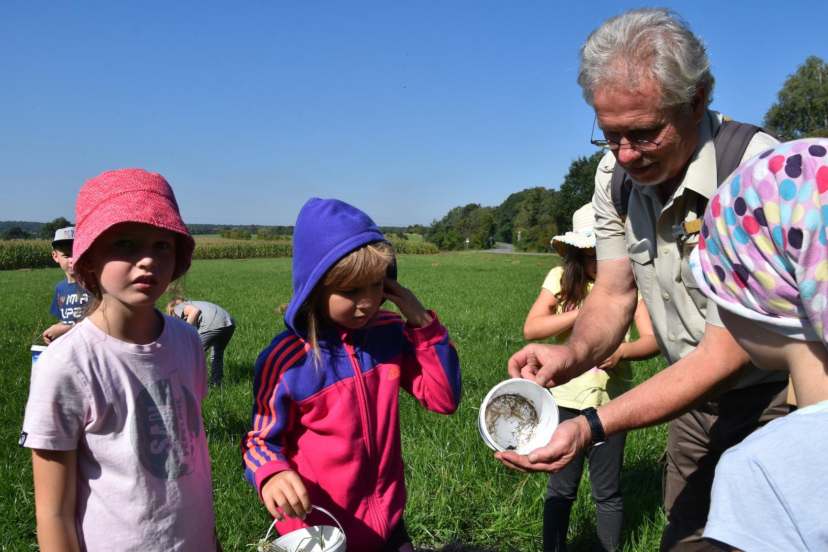 Jörg Nevoigth (Naturwacht Brandenburg) zeigt den Schülerinnen und Schülern eine Feldgrille, das Insekt des Jahres 2003.