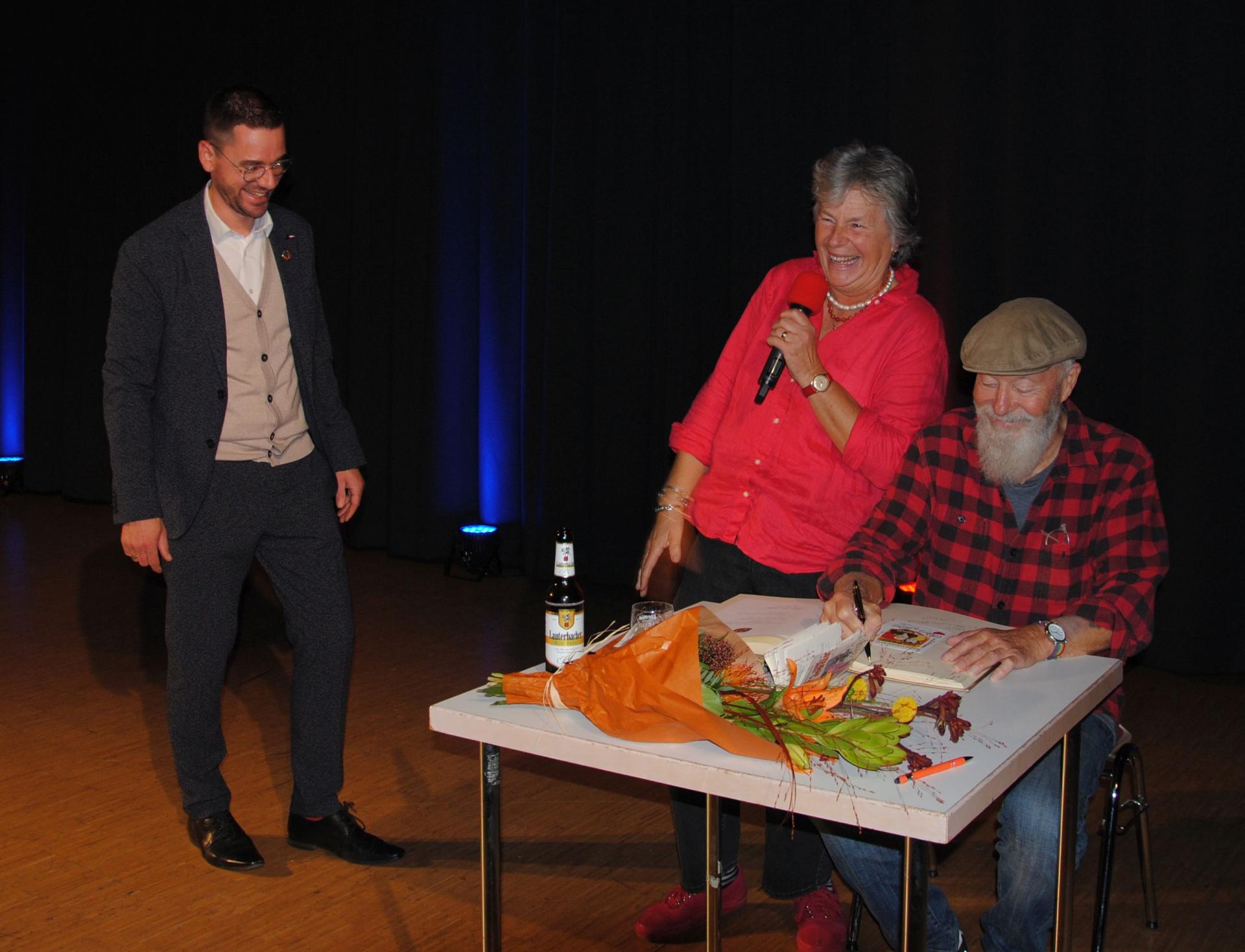 Margie Kinski und Bill Mockridge tragen sich in das Goldene Buch der Gemeinde Großenlüder ein, links Bürgermeister Florian Fritzsch