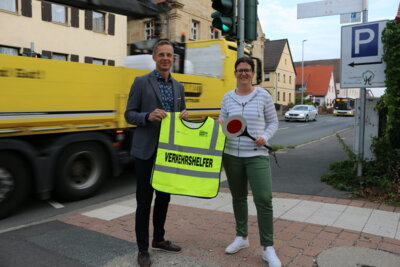 Bürgermeister Holger Bezold überreicht an die Schulweghelfer-Organisatorin Birga Rießland Warnweste und Verkehrskelle für die Sicherheit der schwächsten Verkehrsteilnehmer.