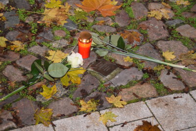 Rolandstadt Perleberg | Abbildung: Stolperstein mit Blumen und Kerze in Gedenken an Adolf Lewandowski, An der Mauer 7.
