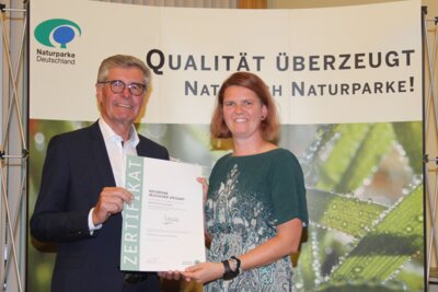 Naturpark-Geschäftsführerin Annika Ludwig nimmt das Zertifikat „Qualitäts-naturpark“ aus den Händen des VDN-Präsidenten Friedel Heuwinkel entgegen. (Bild vergrößern)