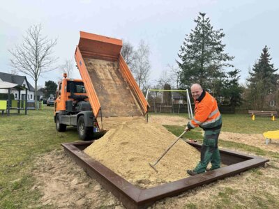 Friedhelm Reinecke vom Betriebshof der Stadt befüllt den Sandkasten in Bentwisch mit neuem Spielkies I Foto: Martin Ferch (Bild vergrößern)