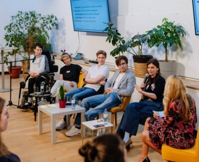 Momentaufnahme der Paneldiskusion. Fünf Menschen diskutieren sitzend. Die Moderatorin ist ihnen zugewandt. (Bild vergrößern)