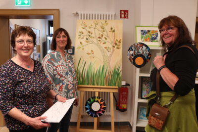 Die beiden Ausstellerinnen Petra Ulm und Birgit Kovac (von links) erklären der Besucherin Regina Klinke verschiedene Maltechniken (Bild vergrößern)