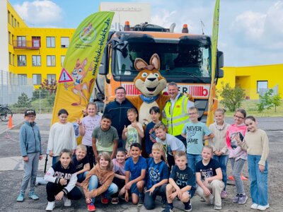 Die Kinder der Klasse 3c der Elblandgrundschule zusammen mit Ordnungsamtsleiter Lars Wirwich (oben links), Maskottchen „Blicki“ und Robert Enge von der Becker Umweltdienste GmbH I Foto: Dirk Hendler (Bild vergrößern)