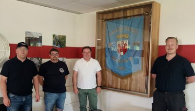 Moritz Gumin (v.l.), Heiko Reinke, Thorsten Bolte und Ortsbrandmeister Andy Bautze vor der neuen Eichen-Vitrine, den Bildern und dem Edelstahlschild. (Bild vergrößern)