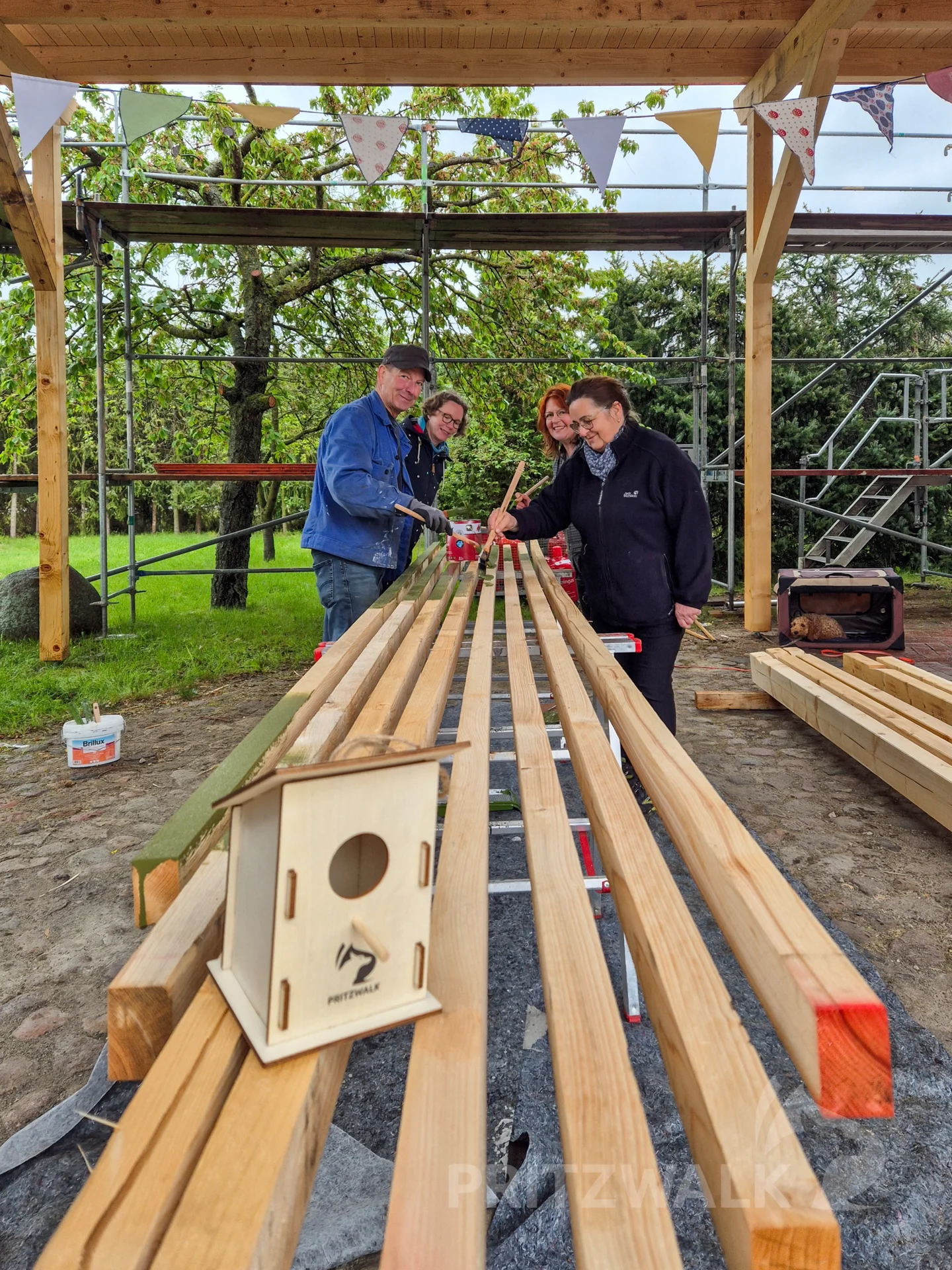 Unter dem Vordach strichen die Ehrenamtlichen Holzlatten für das Vordach beim EKIDZ MiteinanderRaum an. Foto: Stadt Pritzwalk