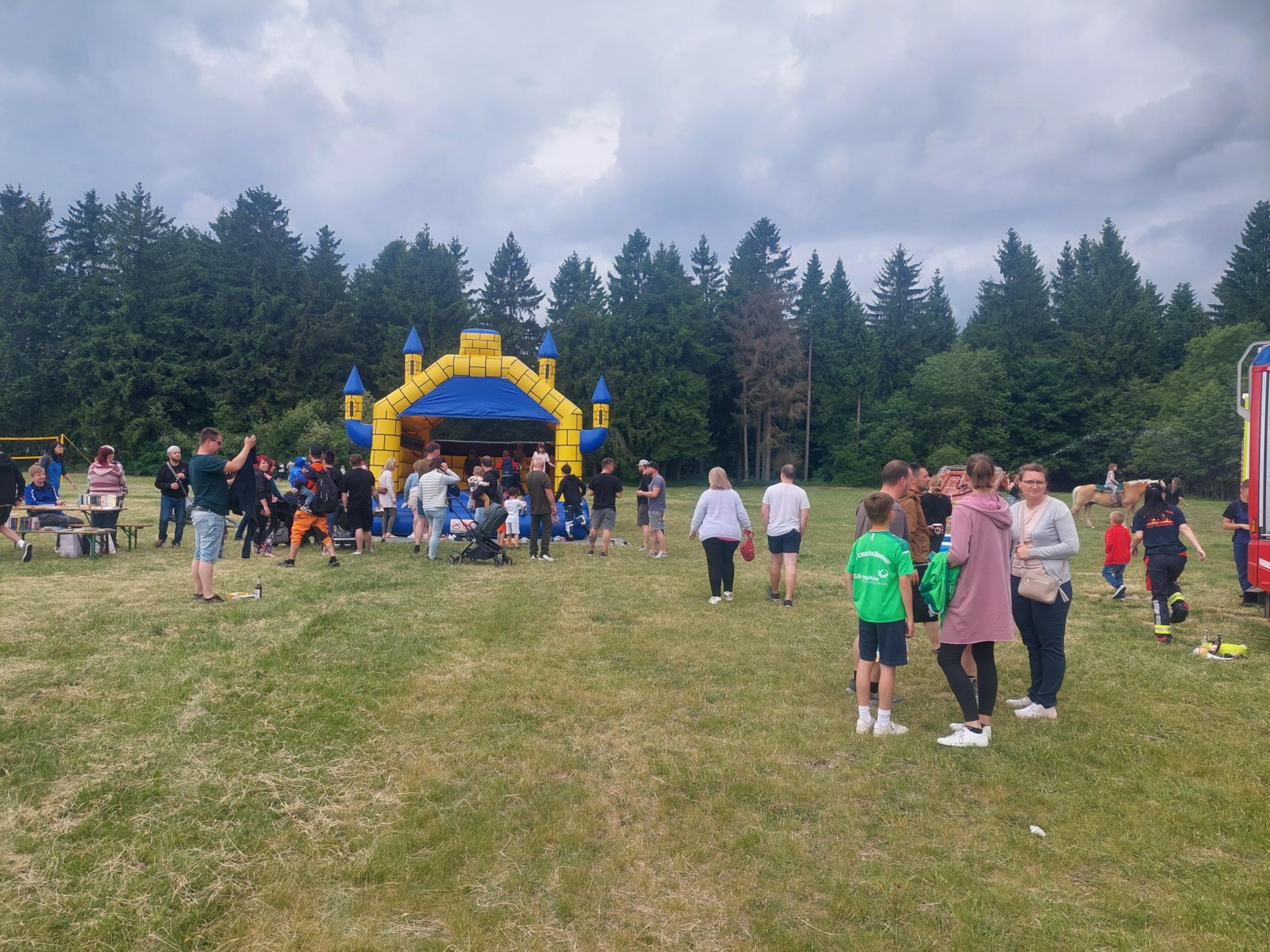 Festbesucher und spielende Kinder auf der Hüpfburg