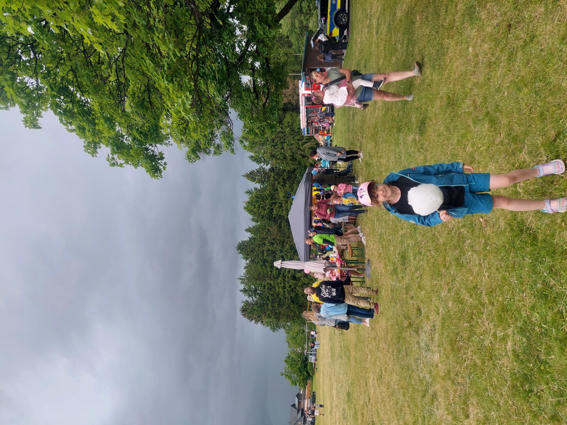 Kind mit Zuckerwatte und feiernden Festbesuchern im Hintergrund
