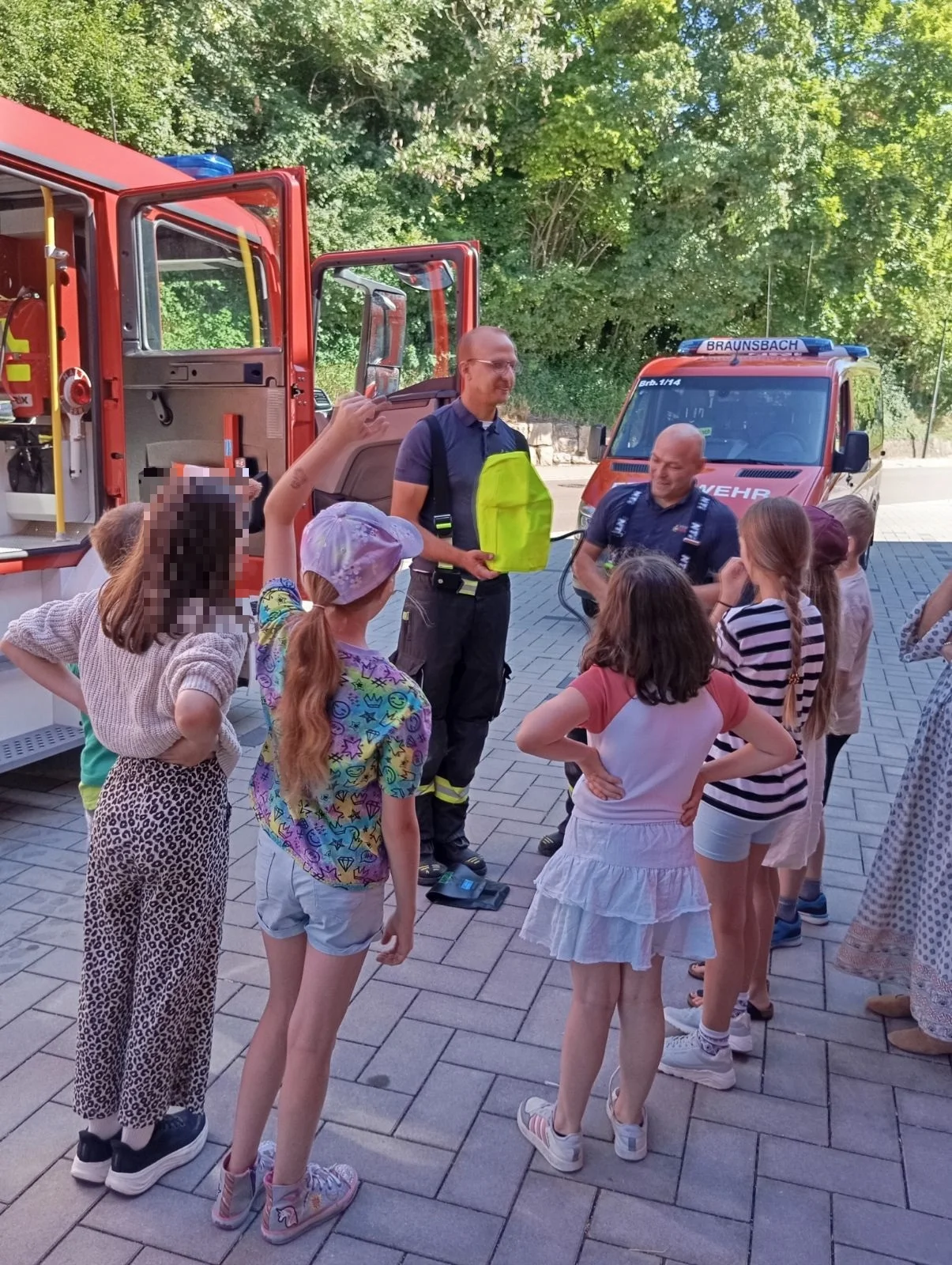 Feuerwehrleute erklären den Kindern etwas