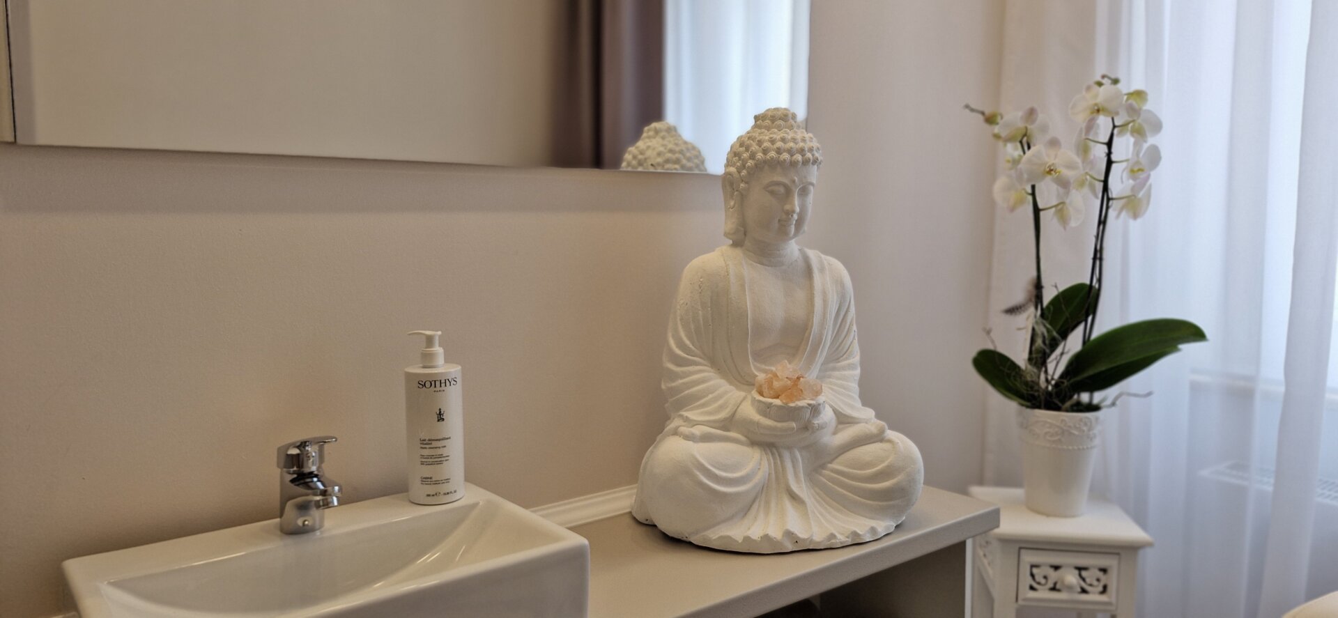 Buddha auf Schrank vor einem Spiegel sitzend