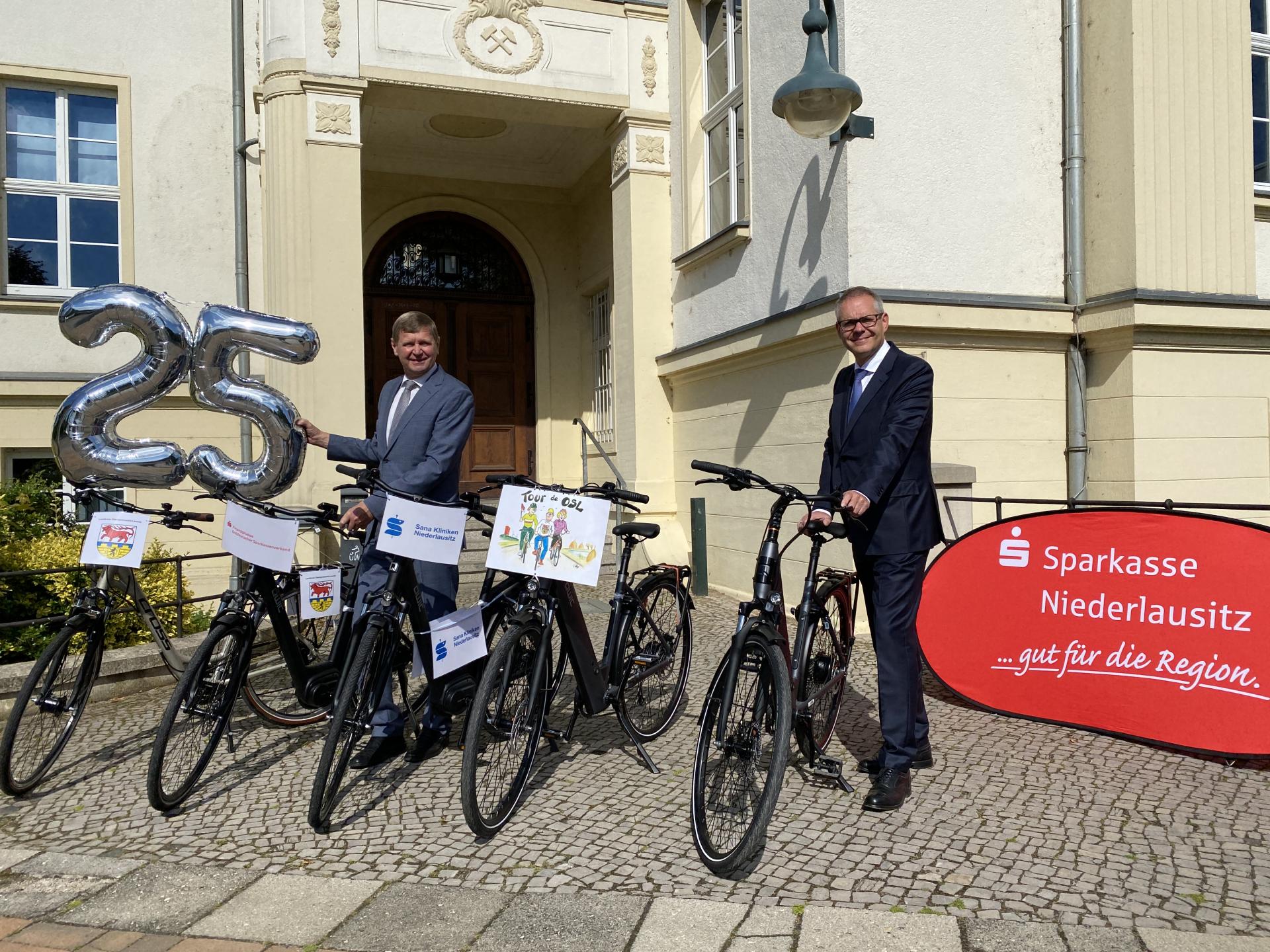 Übergabe der zwei E-Bikes von der Sparkasse durch Marcus Starick an Landrat Heinze und Präsentation der fünf Hauptgewinne der 25. Tour de OSL (Foto: Landkreis OSL / Nora Bielitz)