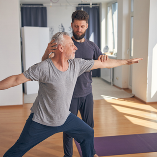 Mann praktiziert Yoga mit Unterstützung