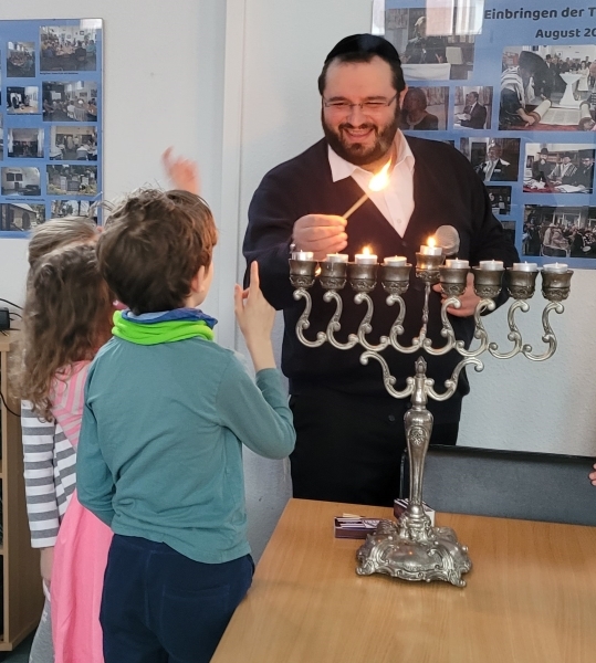 Kinder-Chanukka bei der Jüdischen Gemeinde Kiel und Region. Rabbiner Meir Myropolskyy zündet mit Kindern Chanukka-Kerzen an.