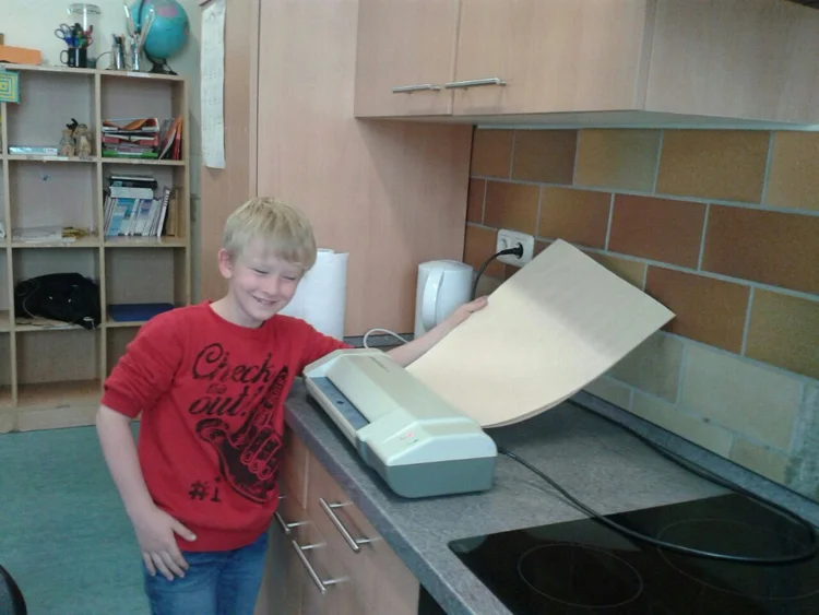 Ein Schüler laminiert sein gemaltes Türschild