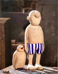 Holzfigur mit Badehose und Pinguien