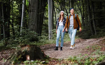 caucasian-couple-friends-walking-with-backpacks-forest