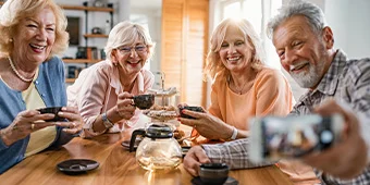 frohliche-reife-freunde-die-spass-haben-wahrend-sie-zu-hause-mit-dem-handy-telefonieren-und-sich-selbst-unterhalten