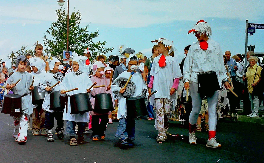 Festumzug zum 4. Kreiserntefest 2004, als Hühner und Hähne verkleidete Kinder und Erwachsene trommeln auf Baueimer