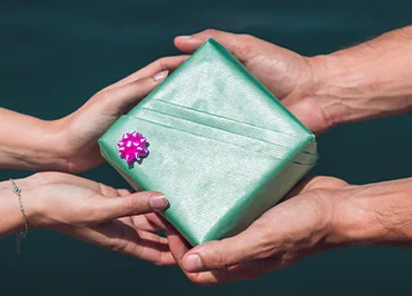 paare-die-grune-geschenkbox-vor-seewasserhintergrund-halten