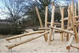 Klettergerüst aus dicken Holzstämmen in einem Sandkasten im Freien